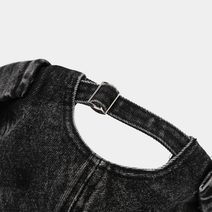 Detail of adjustable silver metal buckle and stitching on washed denim brimless cap