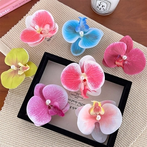 Set of 7 colorful 3D orchid hair clips with pearls on a decorative tray background