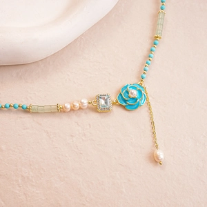 Elegant floral necklace with blue enamel flower, pearls, and crystals on a gold chain