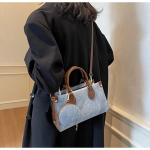 Detail of blue denim texture handbag with brown leather trim and detachable coin purse