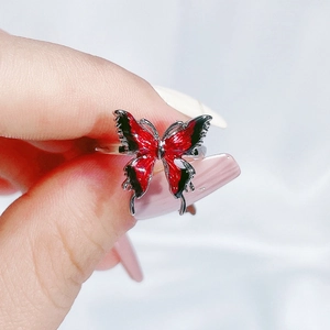 Macro shot of silver ring with detailed red and black enamel butterfly design