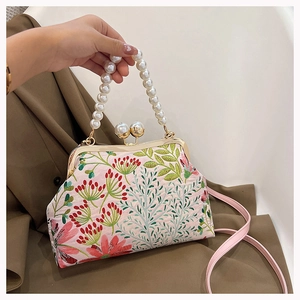 Detail der Blumenstickerei und des Perlengriffs an der eleganten Handtasche im China-Stil