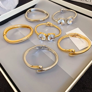 Close-up of elegant gold and silver bangles with clear cubic zirconia in a jewelry tray