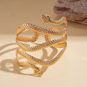 Artistic close-up of a gold double-headed snake cuff bracelet on a desert sand background