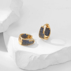 Macro shot of gold hoop earrings with pavé-set blue zircon stones and snap closure