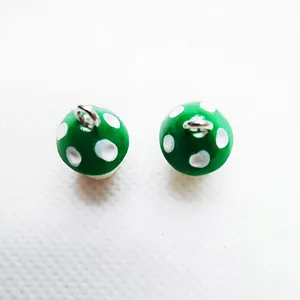 Detail of green resin mushroom pendant with white dots and silver metal ring for DIY jewelry
