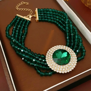 Detailed view of emerald green multi-strand beaded bracelet with gold rhinestone charm