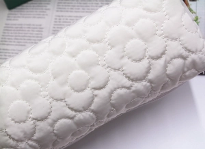 Detail of white quilted flower pattern on soft fabric stationery bag with premium stitching