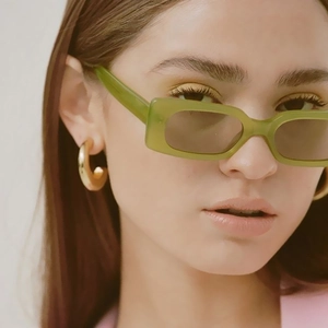 Fashionable olive green rectangular sunglasses shown on a model with elegant gold earrings