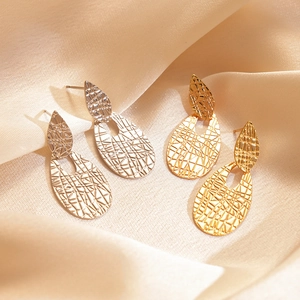 Textured metal teardrop earrings in gold and silver finish on silk fabric