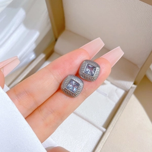 Macro view of silver titanium steel stud earring with a square zircon and vintage wavy edges