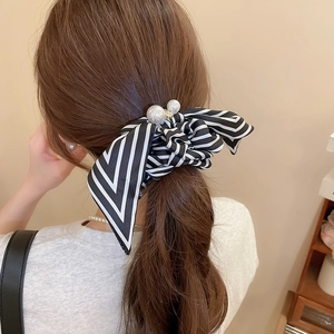 Detailed view of striped bow hair tie with pearls and rhinestones on hair