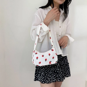 White nylon shoulder bag with red strawberry pattern shown on model in a casual outfit