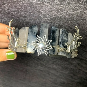 Detail of handmade silver branch crown with sun motif and raw black and white quartz stones