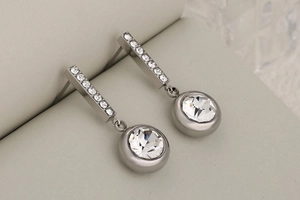 Detailed close-up of geometric silver drop earrings with square pavé studs and round diamond charms