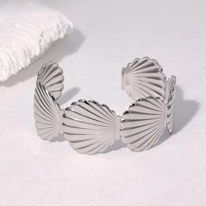 Detailed view of a silver scalloped open cuff bracelet on a minimalist white stone surface