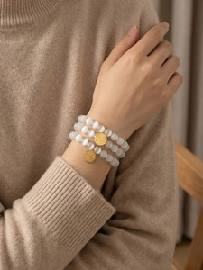 Detailed view of triple-layer cat's eye bead bracelet with gold Fu character pendants