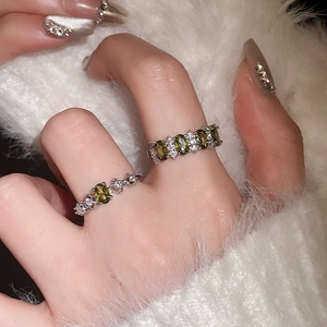 Macro shot of silver ring set featuring oval olive green gems and sparkling crystals