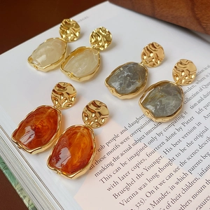 Gros plan de boucles d'oreilles irrégulières en résine avec métal doré martelé sur livre