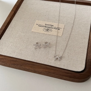 Detailed view of silver bow jewelry set with micro-pave crystals on fabric tray
