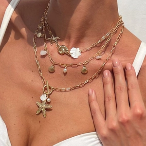 Gold layered ocean-style necklace with starfish, seashell pendants and pearls on model