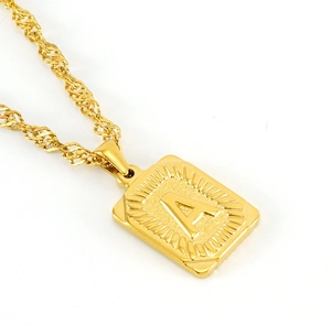 Macro shot of gold-plated square pendant necklace featuring engraved letter A texture