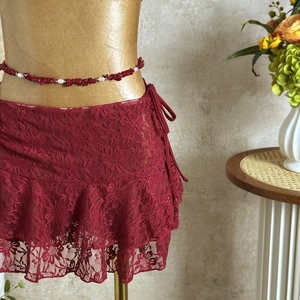 Detail of dark red lace ruffle mini skirt with beaded bohemian waist chain accessory