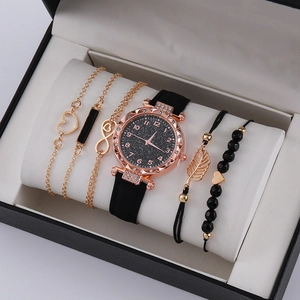 Makroansicht der roségoldenen Damenuhr und vier Armbänder in einer schwarzen Geschenkbox