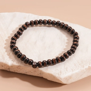 Close-up of vintage brown wood beads bracelet showing natural grain texture on a stone