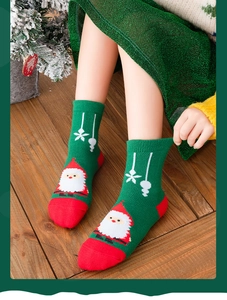 Detail of Christmas themed knitted socks with Santa Claus pattern on a wooden floor