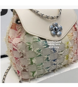 Close-up of colorful woven fabric and silver camellia flower buckle on the chain backpack