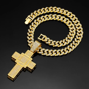 Detail of gold Cuban chain and cross pendant with clear crystals on black reflective background