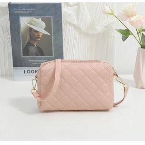 Detailed view of pink quilted crossbody bag with gold hardware and matching strap