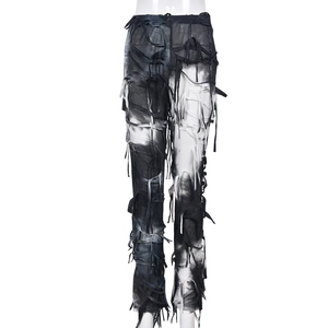Dettaglio macro dei pantaloni tie-dye bianchi e neri con bordi sfilacciati e nappe