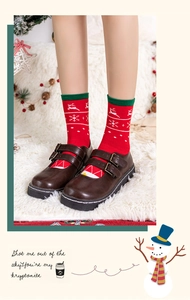 Detail of Christmas crew socks with reindeer patterns worn with dark brown Mary Jane shoes