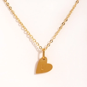 Détail du pendentif cœur doré avec la lettre U gravée sur une fine chaîne élégante