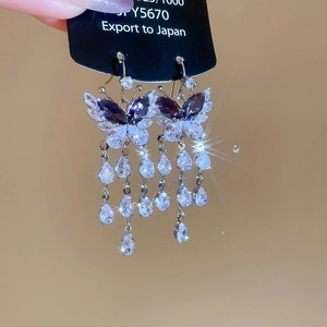 Detail shot of silver butterfly tassel earrings with purple pear-cut zircon crystals
