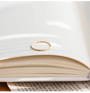 Macro shot of minimalist gold titanium ring with three tiny zircon stones on book pages