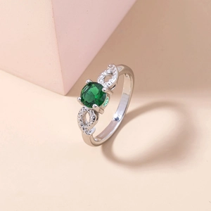 Detailed macro view of silver ring featuring a round green gemstone and micro-pave zircons