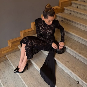 Detailed view of elegant black lace dress with long sleeves and flowing fabric train detail