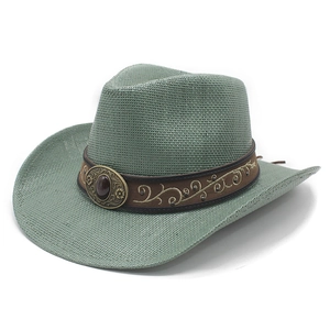 Close-up of green straw cowboy hat featuring brown band with gold embroidery and red gemstone