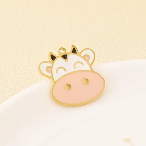 Macro view of cute cartoon cow enamel pendant with golden stainless steel edges and horns