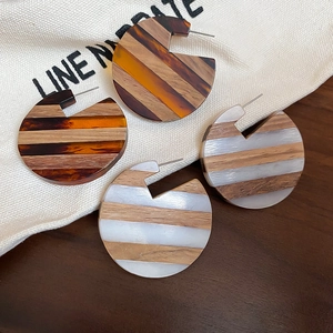 Detailed view of C-shaped hoop earrings featuring wood grain and resin stripe textures