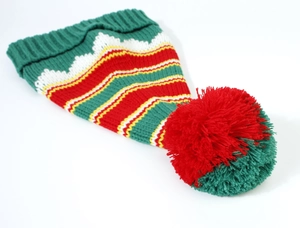 Detail of a knit Christmas elf hat with colorful zigzag patterns and a large pom-pom topper