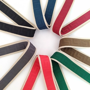 Macro view of wide woven bag straps in various colors with Greek Key geometric pattern