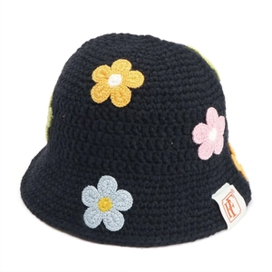 Close-up of crochet knit black bucket hat featuring colorful floral appliques and side tag