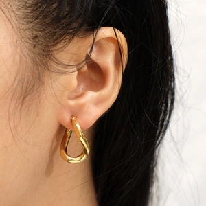 Golden irregular teardrop earrings with a polished finish worn by a model