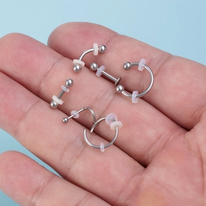 Silicone piercing healing discs and stainless steel studs set held in palm of hand