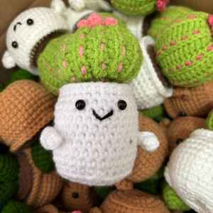 Close-up of hand-crocheted green cactus doll with intricate knitting texture and pink flower