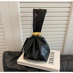 Detail view of black drawstring bucket bag featuring unique pebble gold metal hardware